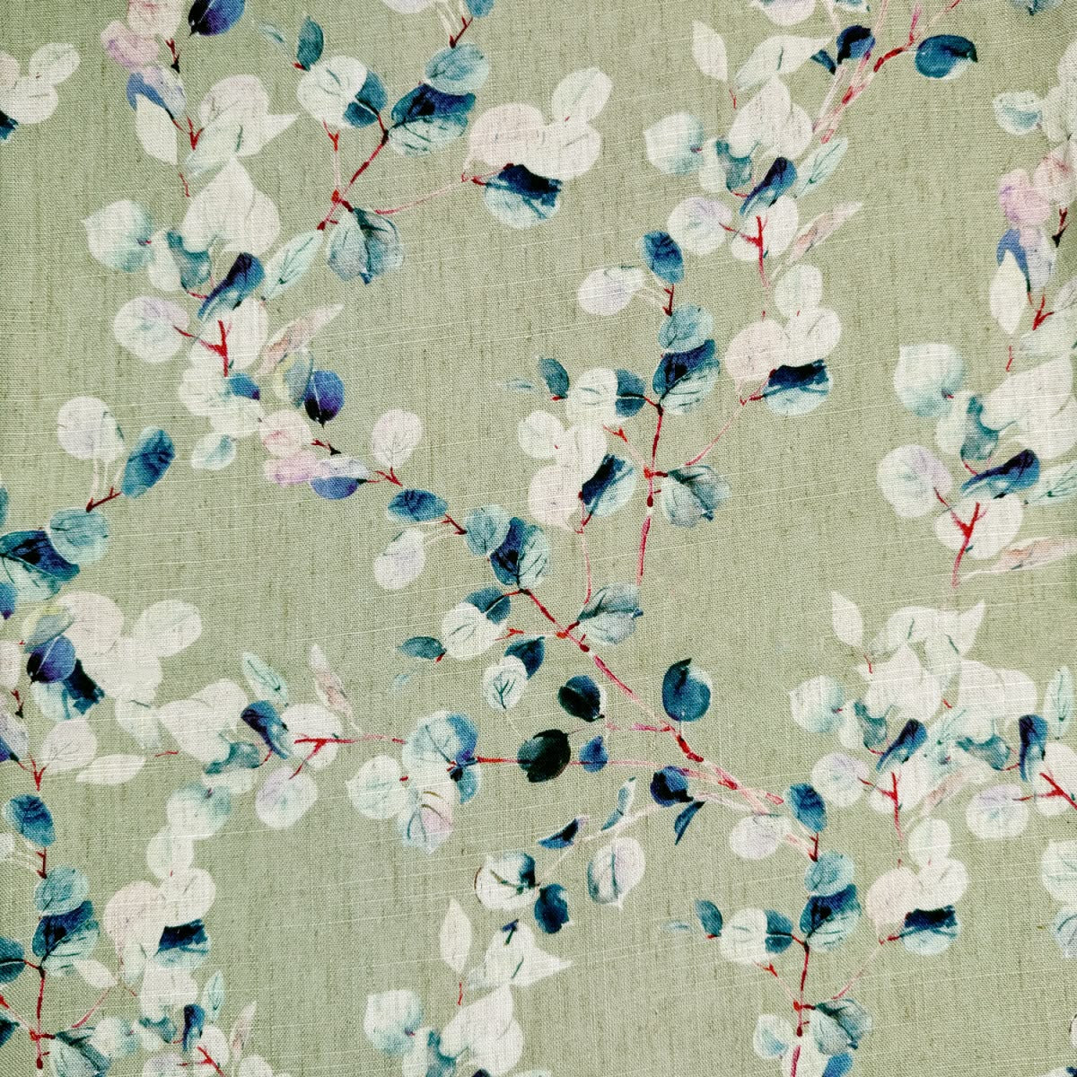 A close-up of a fabric pattern featuring watercolor-style eucalyptus leaves in shades of blue, navy, white, and soft pink on a muted sage green background.