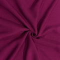 A close-up of draped fabric in a rich magenta-purple color, arranged in a central swirl to show the material's texture and drape.