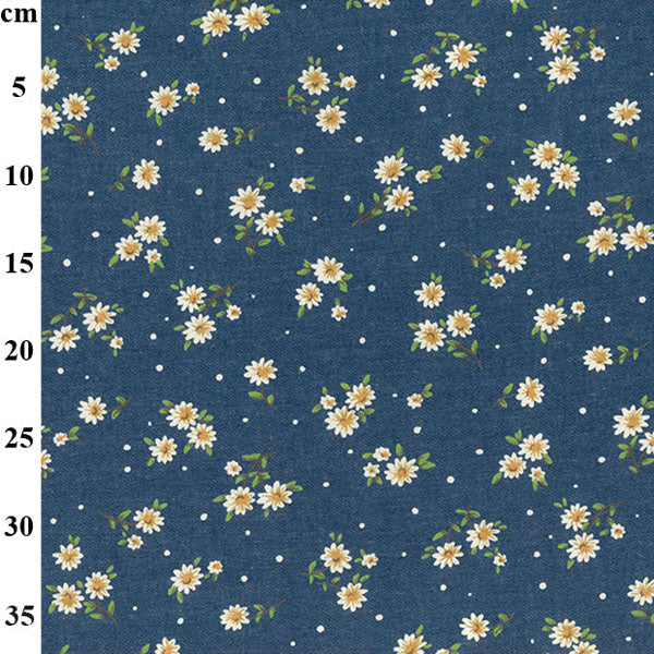 A close-up of a navy blue fabric with a repeating pattern of small white daisies with yellow centers, green stems, and scattered white dots, with a vertical measurement scale in centimeters on the left side.