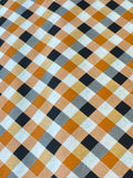 A close-up of a plaid fabric pattern with diagonal stripes in orange, black, white, and gray.