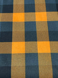 A close-up of a buffalo plaid fabric pattern featuring alternating blocks of mustard yellow and dark navy blue with a visible diagonal twill weave texture.