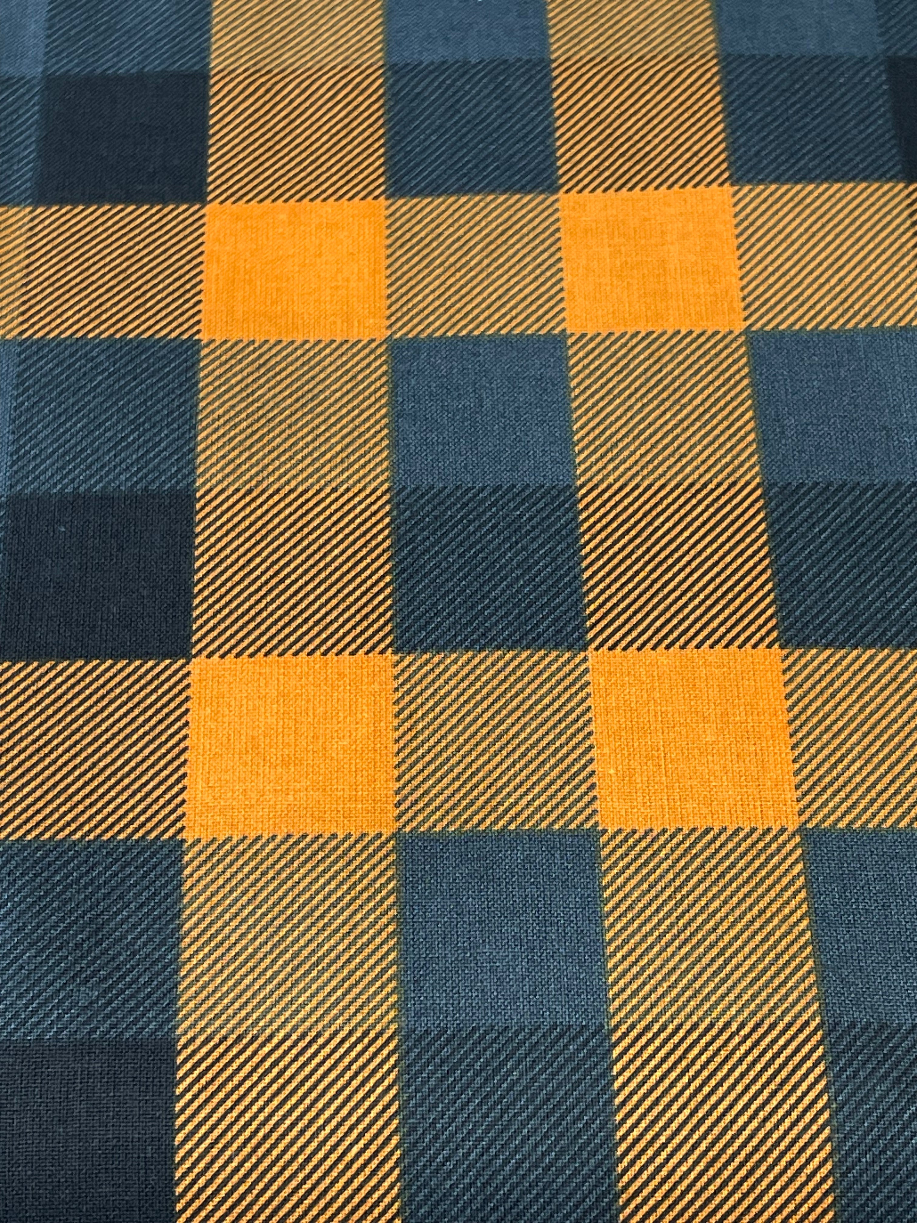 A close-up of a buffalo plaid fabric pattern featuring alternating blocks of mustard yellow and dark navy blue with a visible diagonal twill weave texture.