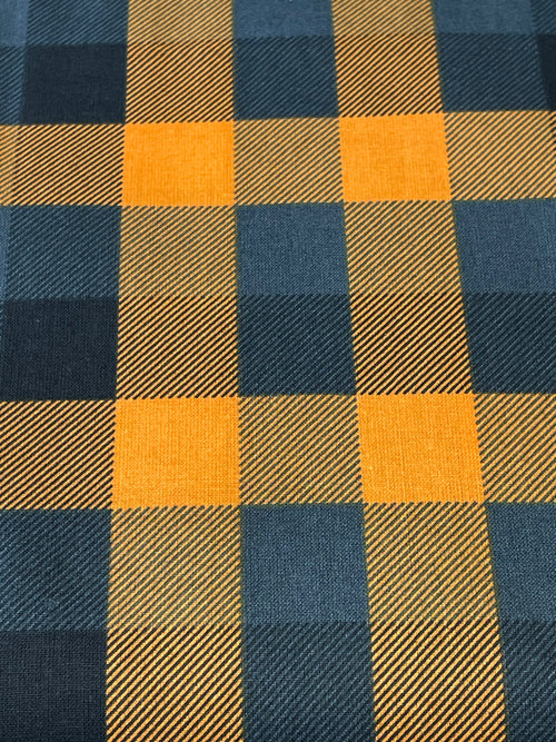 A close-up of a buffalo plaid fabric pattern featuring alternating blocks of mustard yellow and dark navy blue with a visible diagonal twill weave texture.