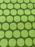 A close-up of fabric with a repeating pattern of light green rounded circles on a darker olive green background.