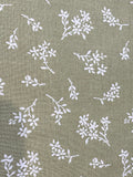 Olive green fabric with a white floral and leaf print pattern.