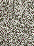 A close-up of a fabric pattern featuring a dense, repeating design of small olive green and dusty purple circles on a white background.