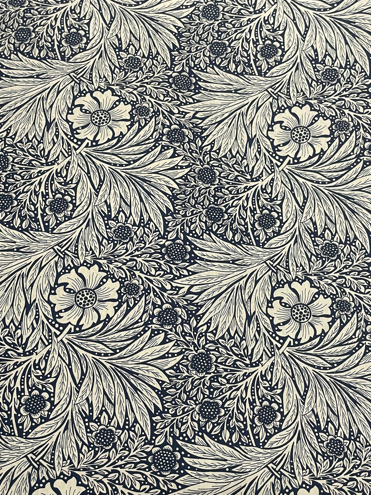 A close-up of a repeating floral and leaf pattern in dark navy blue and warm off-white, filling the entire frame.