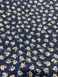 A close-up of a navy blue fabric with a repeating small floral pattern in cream, light blue, and tan.