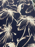 A close-up of a dark navy blue fabric with a cream-colored floral print, showing the texture of the material.