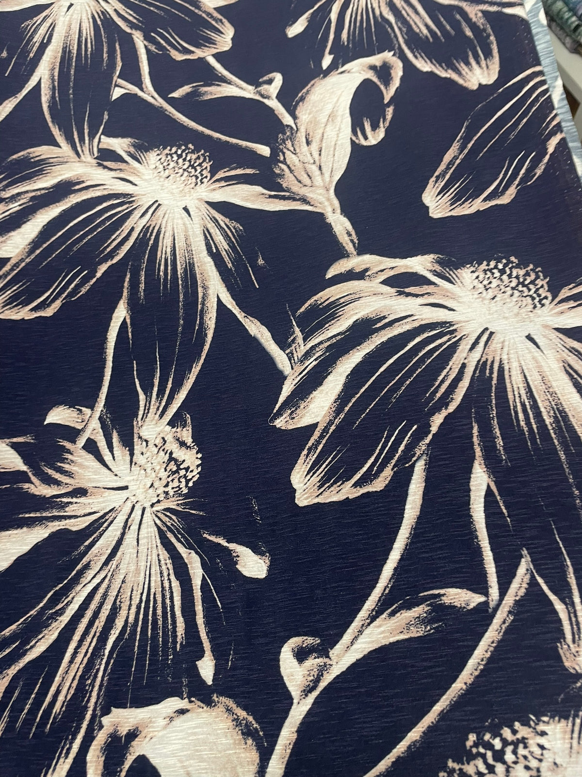 A close-up of a dark navy blue fabric with a cream-colored floral print, showing the texture of the material.