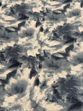 A close-up of a fabric pattern featuring an abstract, textured design in charcoal gray, slate blue-gray, and cream.