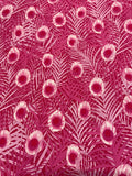 A close-up of a fabric pattern featuring stylized pink and magenta palm leaves with circular floral eye motifs.