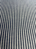 A close-up of a woven fabric with narrow vertical navy blue and off-white stripes.