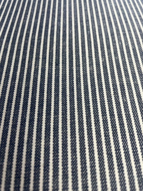 A close-up of a woven fabric with narrow vertical navy blue and off-white stripes.