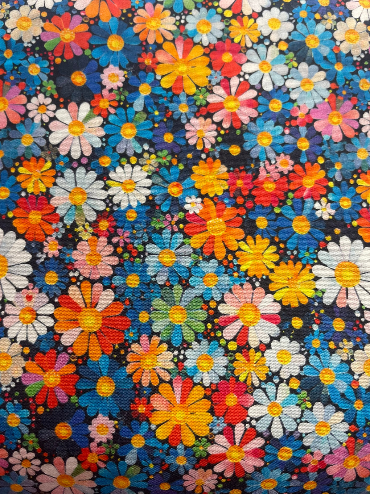 A close-up of a dense floral pattern featuring multicolored daisies and small flowers on a dark navy background.