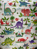 A close-up of a white fabric printed with a colorful dinosaur safari pattern, featuring various dinosaurs in green, blue, red, and purple among palm trees and plants.