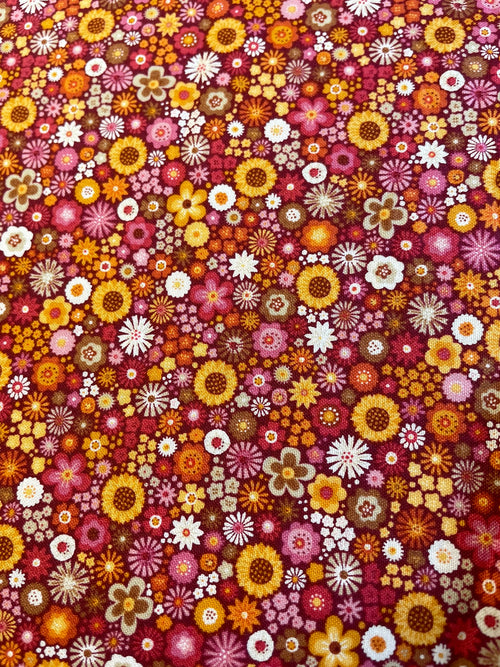 A dense, all-over floral pattern featuring small daisy-like flowers in yellow, orange, pink, red, white, and brown on a dark red background.