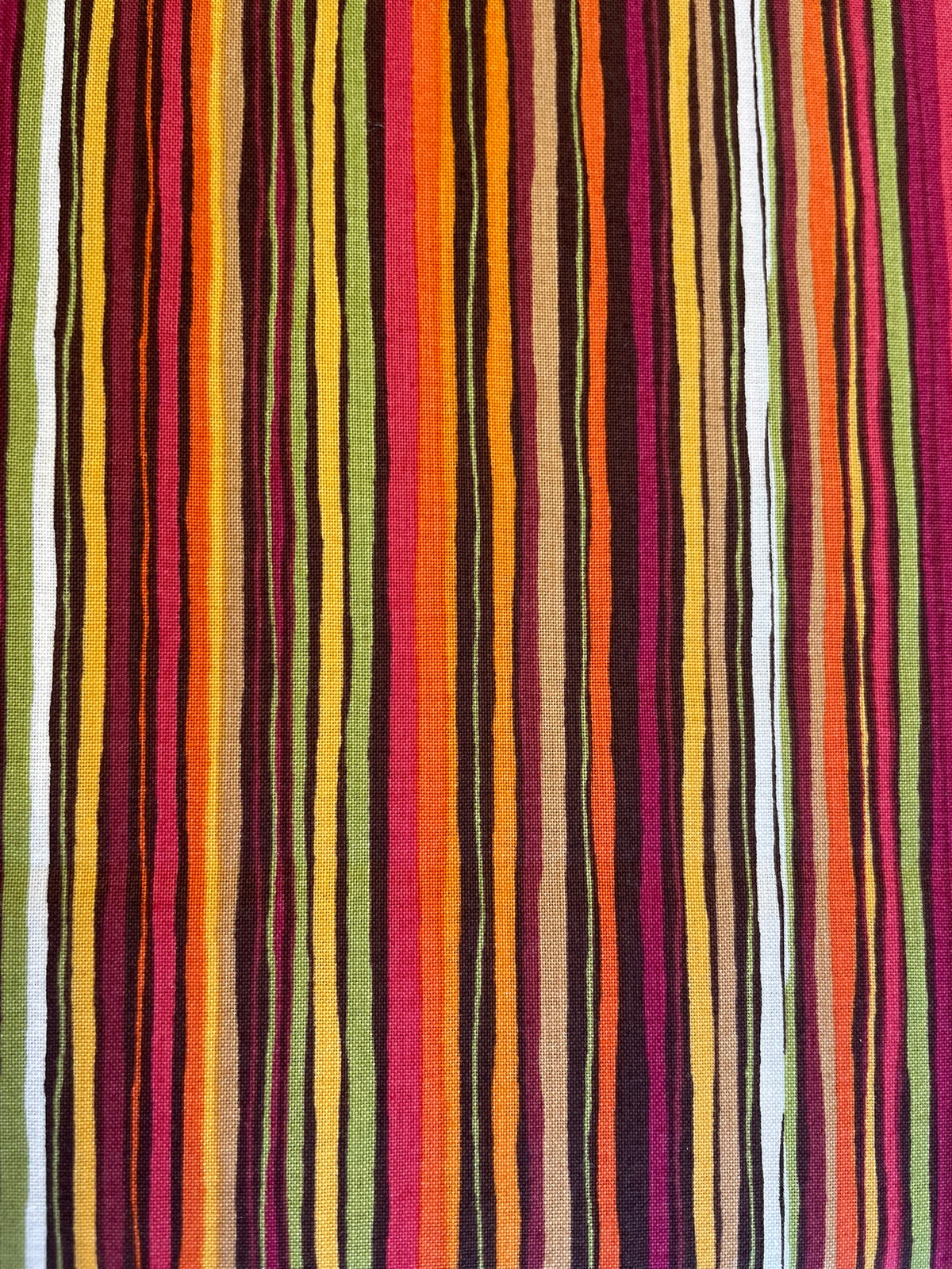 A close-up of a striped textile with vertical bands in olive green, black, brown, yellow, orange, red, pink, and white.
