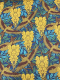 A close-up of a fabric pattern featuring flying birds and yellow flower clusters on a blue background with teal leaves.