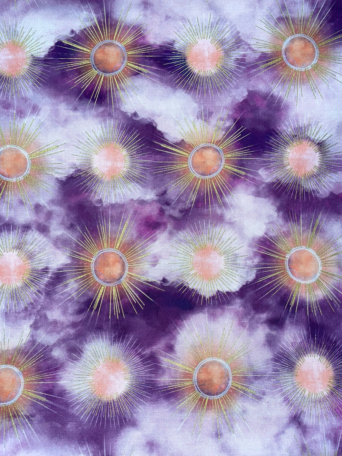 A repeating pattern of stylized sunburst motifs in purple, lavender, peach, and pale yellow, arranged across a cloudy abstract background.