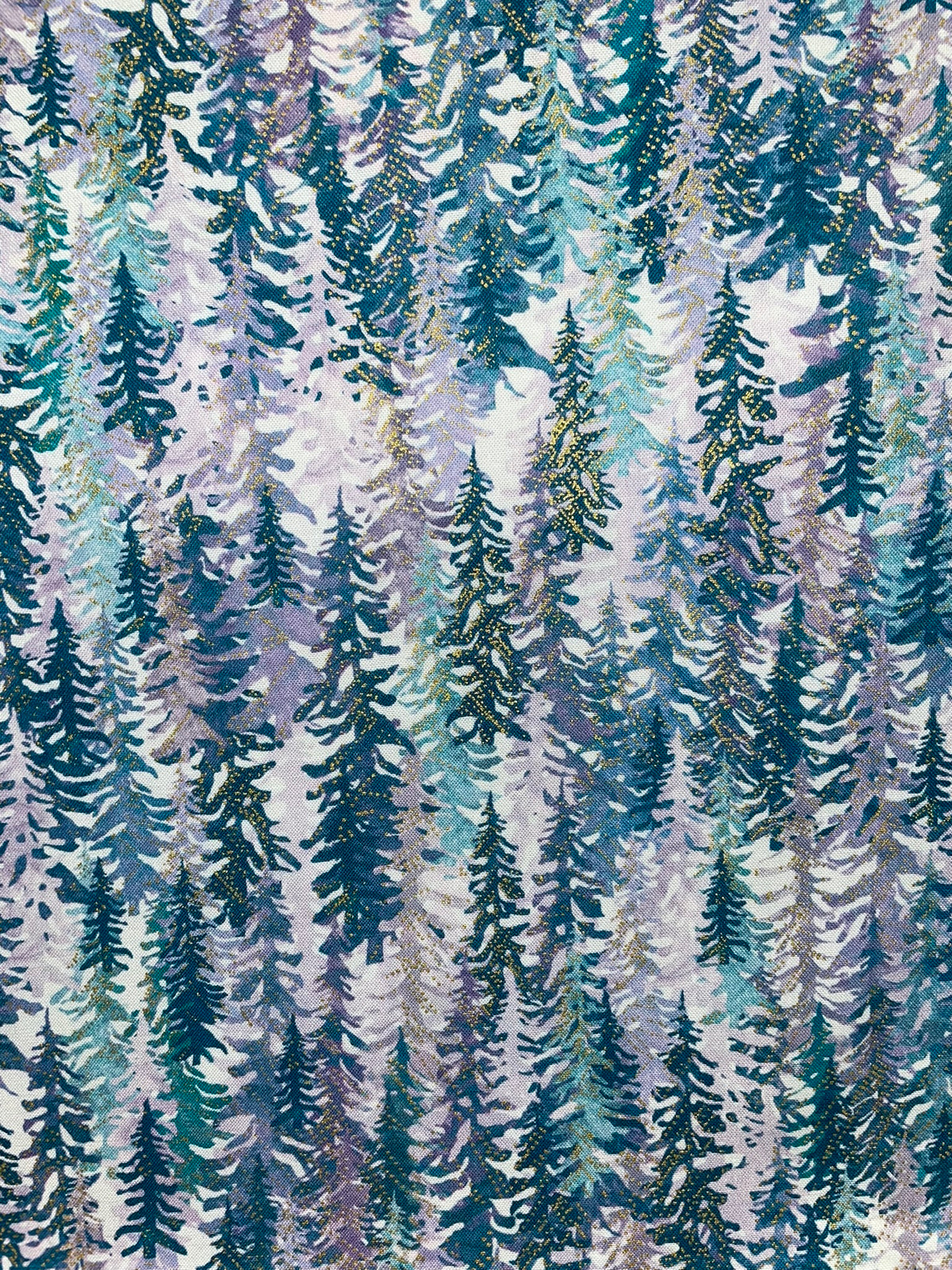 A repeating pattern of stylized evergreen trees in shades of blue, teal, green, lavender, and gray on a light background.