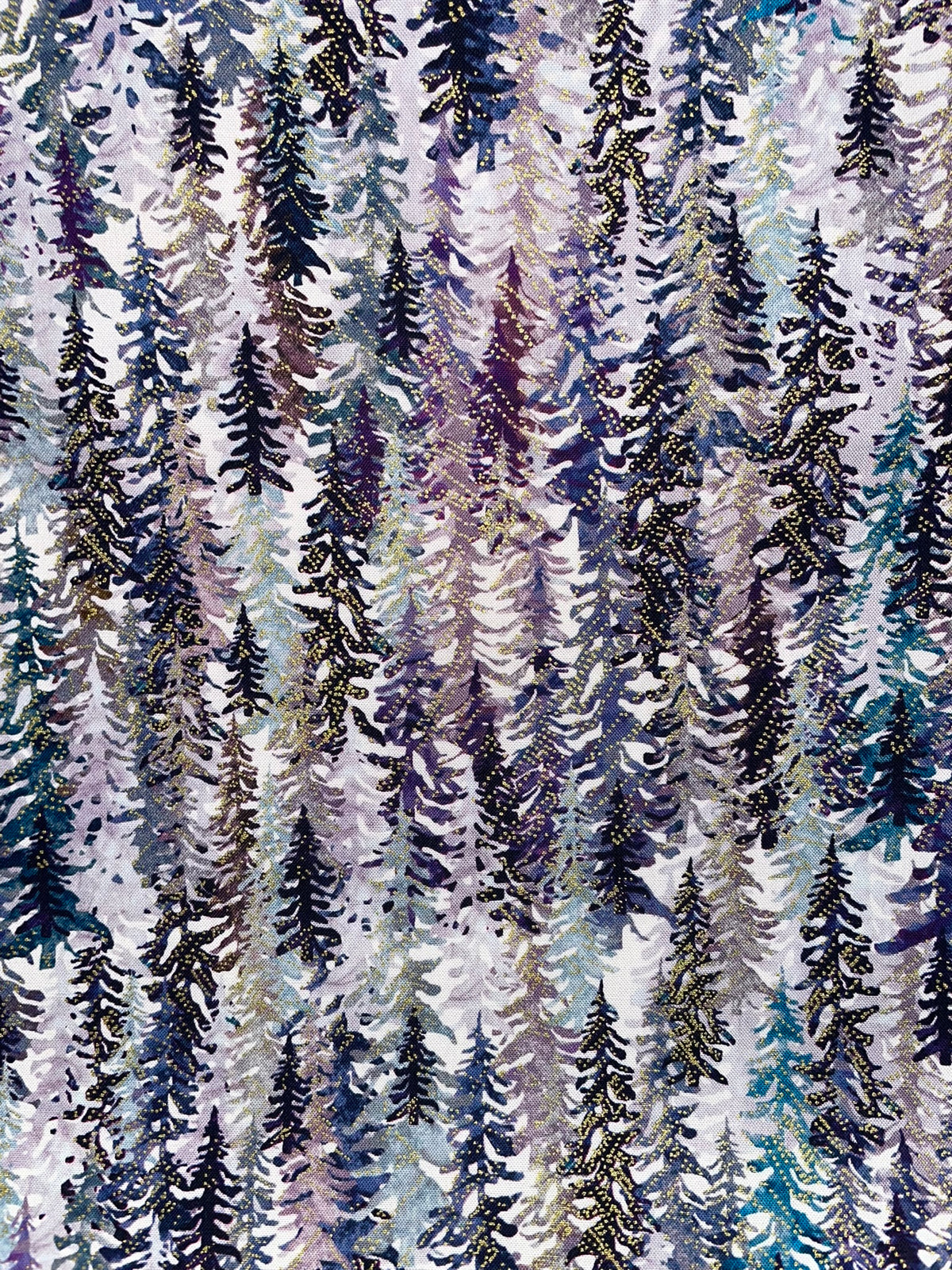 A close-up of a fabric pattern featuring vertical rows of pine trees in winter foliage, with colors including navy, purple, blue, black, and gold on a light background.
