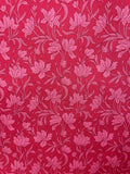 A close-up of a red and pink floral patterned fabric with a repeating damask-style floral design.