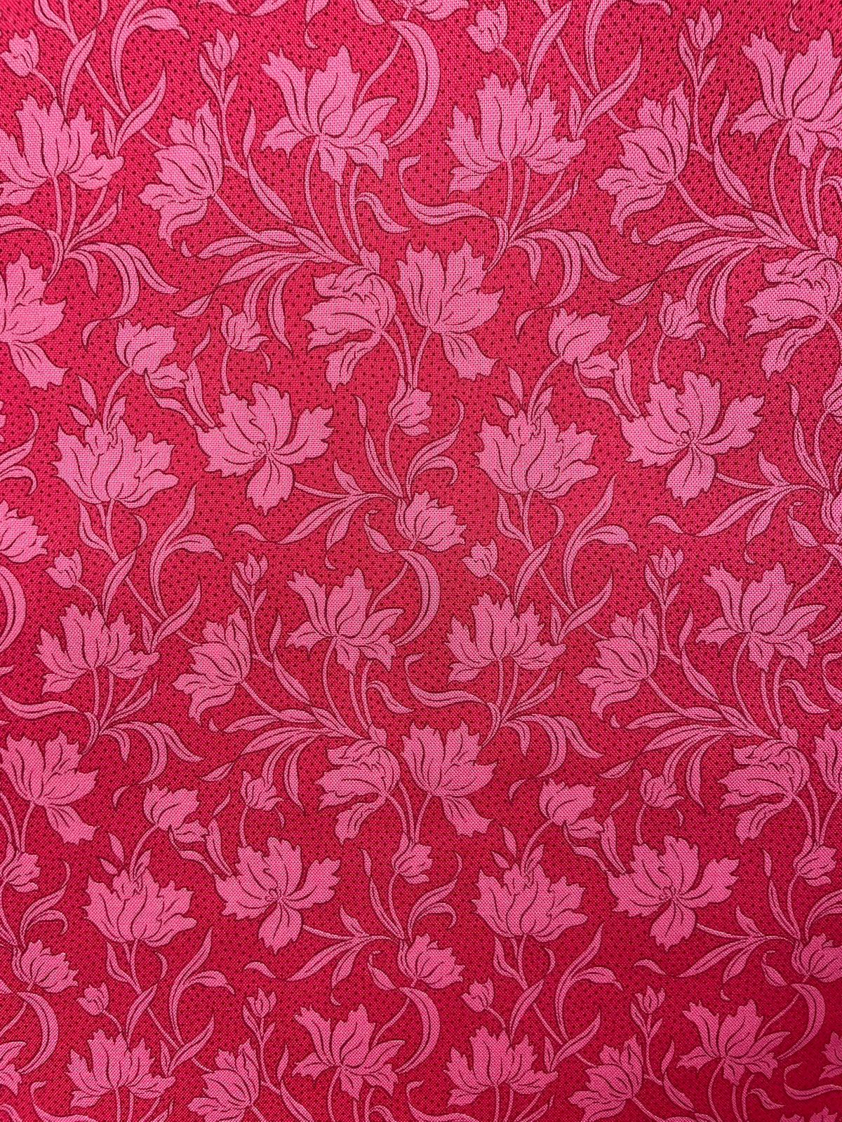 A close-up of a red and pink floral patterned fabric with a repeating damask-style floral design.