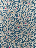 A close-up of a fabric pattern featuring navy blue leaves and branches with small tan dots and scattered red berries on a cream background.