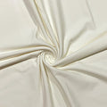 A close-up of cream-colored fabric arranged in a spiral drape, showing its smooth texture and soft folds.