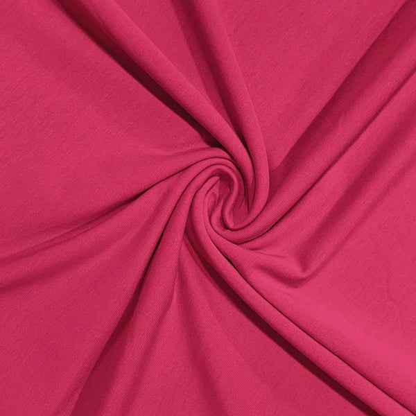 A close-up of bright pink fabric arranged in a spiral drape, showing the material texture and color.