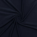 A close-up of dark navy blue fabric arranged in a spiral drape, showing the material's texture and color.