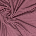 A close-up of draped dusty rose fabric arranged in a spiral pattern, showing its soft texture and color.