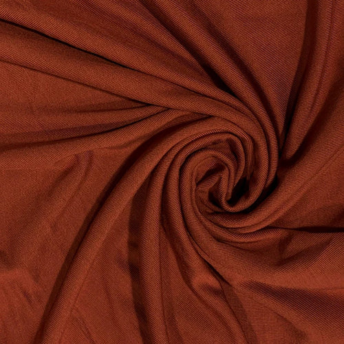 A close-up of draped rust-brown fabric arranged in a spiral, showing the material texture and color.