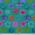 A close-up of a fabric pattern featuring colorful flowers on a green background with white polka dots. The design includes teal, pink, purple, and green floral motifs, with a white measurement ruler visible along the bottom edge.