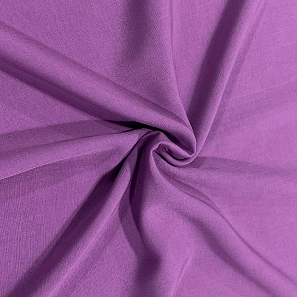 A close-up of draped purple fabric arranged in a spiral twist, showing the material's texture and color.