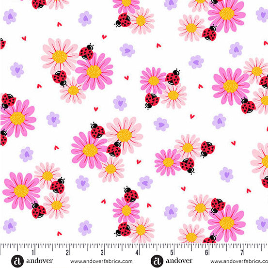 A repeating fabric pattern featuring pink daisies with yellow centers, purple flowers, red ladybugs, and small red hearts on a white background, with a ruler and andover branding along the bottom edge.