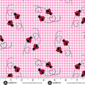 Pink gingham fabric with a repeating pattern of red and black ladybugs on black curved vines, shown with a white measurement ruler along the bottom edge.