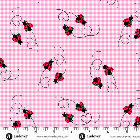 Pink gingham fabric with a repeating pattern of red and black ladybugs on black curved vines, shown with a white measurement ruler along the bottom edge.